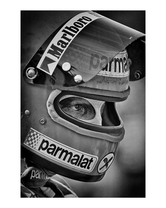 Black-and-white close-up of a Formula One driver wearing a Parmalat racing helmet, from Richard Kelley's Golden Era F1 archive.